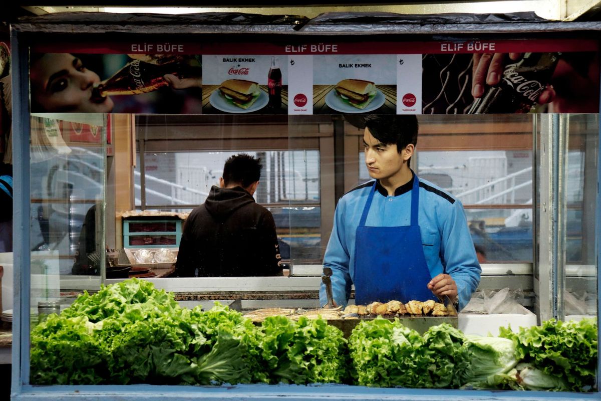 A vendor at a sandwich stall in Istanbul prepares food with fresh lettuce.