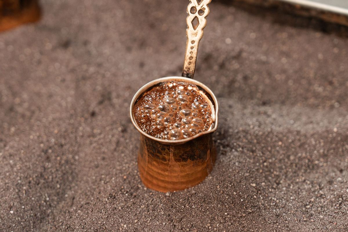 Close-up of Turkish coffee brewing in a copper cezve, showcasing rich foam and traditional preparation.